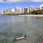 A snorkeler explores the reefs off Oahu's Waikiki Beach, a great place for snorkeling in Hawaii.